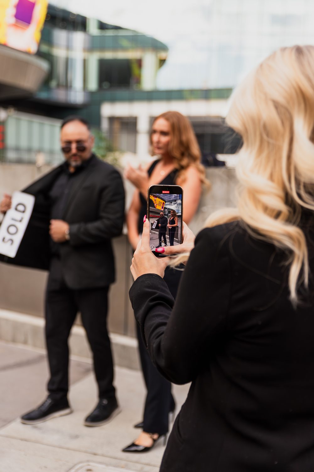 Makayla filming a client's 'SOLD' moment on her phone.